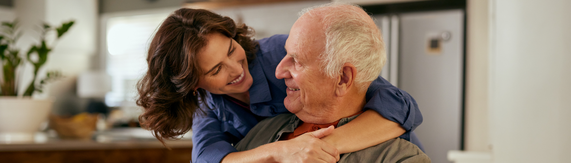 Lovely adult daughter embracing senior father from behind