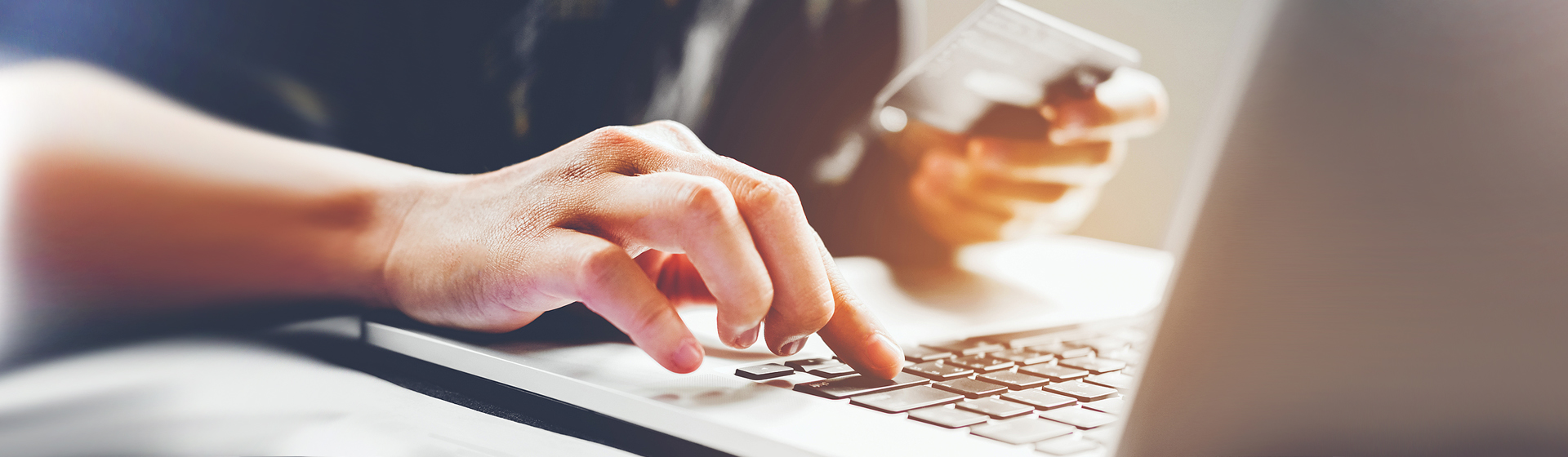 man typing on laptop keyboard and holding credit card