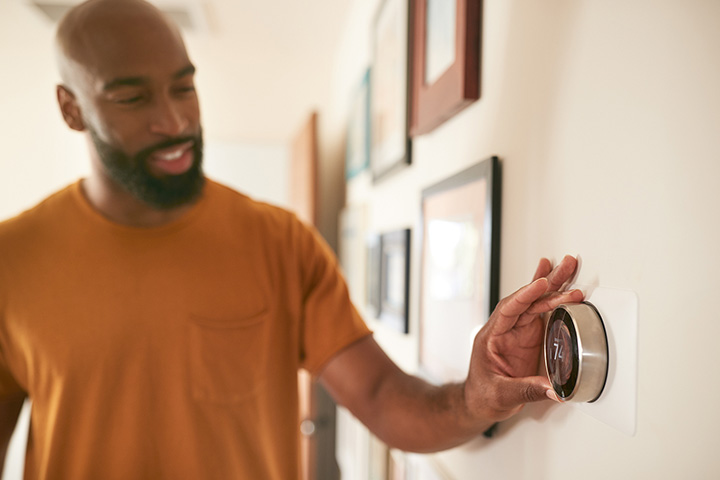 man adjusting thermostat on the wall