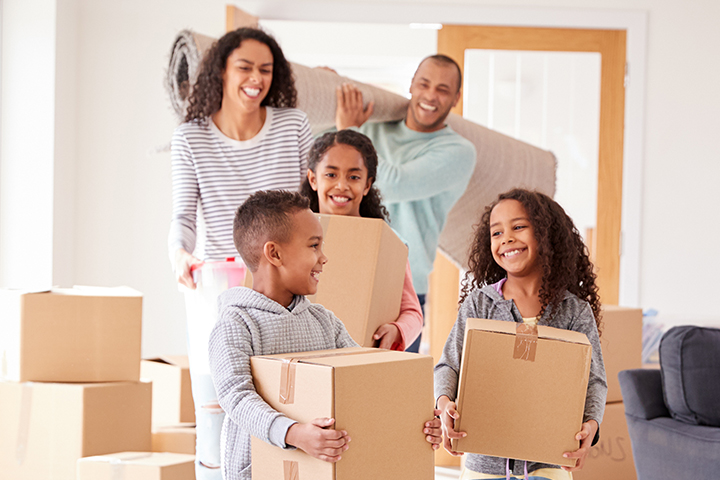 family carrying boxes moving into home